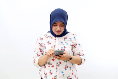 Happy asian muslim woman standing while holding a cell phone. Isolated on white background
