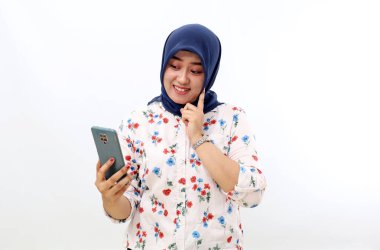 Happy asian muslim woman standing while holding a cell phone. Isolated on white background