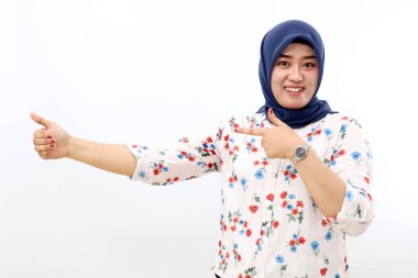 Happy asian muslim woman pointing sideways. Isolated on white background.