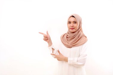Boşluğu işaret eden genç müslüman kadın portresi. Beyazda izole edilmiş