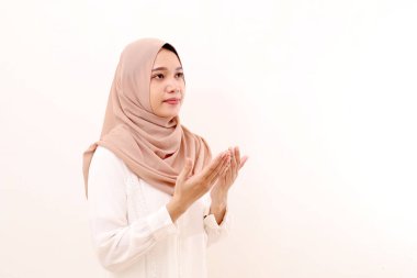 Genç Asyalı Müslüman kadın dua eden bir el hareketiyle ayakta duruyor. Beyazda izole edilmiş