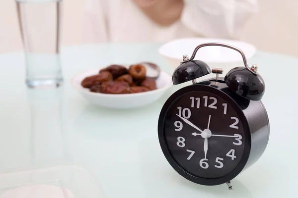 Close up photo of clock on the table. Breaking fast time concept. Ramadan concept.