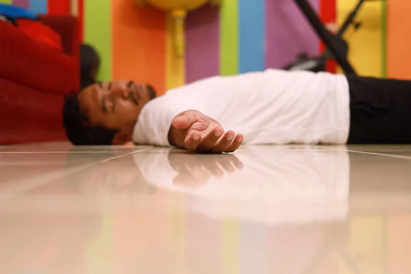 Asian adult man lying unconscious on the floor at home. Selective focus on hand