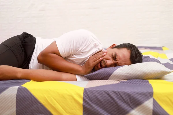 Pria Asia Berbaring Tempat Tidur Rumah Sambil Memegang Pipinya Konsep — Stok Foto