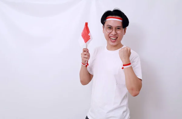 アジアの男は旗と精神的なジェスチャーを保持することによってインドネシアの独立記念日を祝う — ストック写真