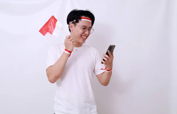 亚洲人拿着手机和国旗庆祝印度尼西亚独立日 与白种人隔离 — 图库照片