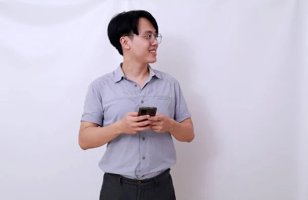 Feliz Asiático Homem Segurando Telefone Celular Enquanto Olha Para Lado — Fotografia de Stock
