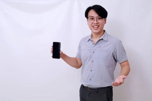 ブランクの携帯電話のディスプレイを提示しながら立って幸せなアジア人男性 白に隔離された — ストック写真