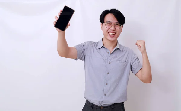 快乐而成功的亚洲男人紧紧抓住自己的手 展示空白手机 — 图库照片
