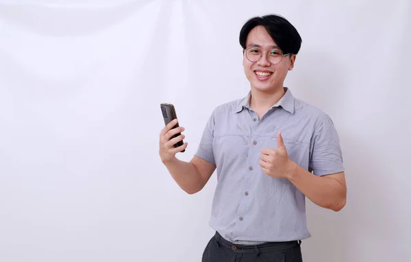 親指を立てながら携帯電話を持っている幸せなアジア人男性 白に隔離された — ストック写真