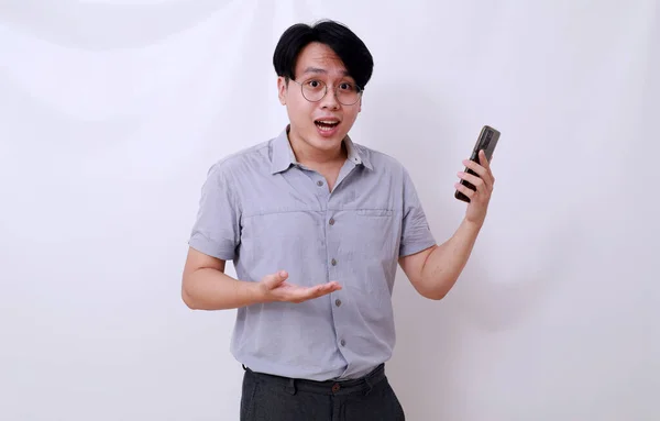 Förvirrad Asiatisk Man Som Håller Mobiltelefon Medan Han Visar Gest — Stockfoto
