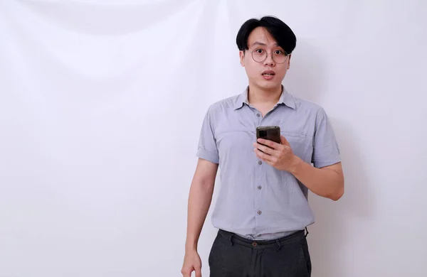 被吓坏了的亚洲男人拿着一个表情混乱的手机 与白种人隔离 — 图库照片