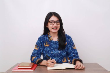 Batik Korpri giyen Asyalı kadın, Endonezya 'nın geleneksel işçi üniforması ofis masasında.