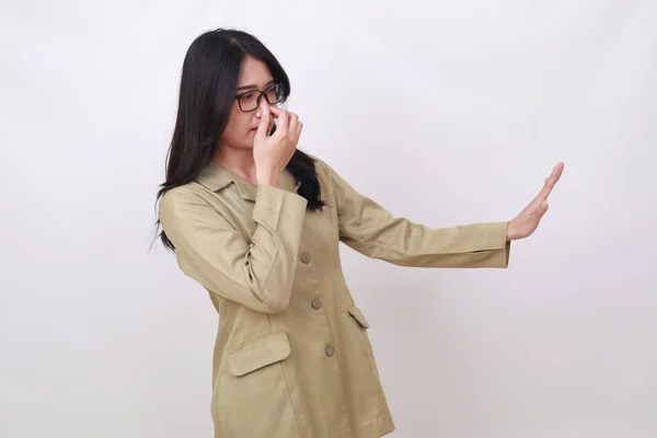 Young indonesian civil servant covering her nose and denied something from side. Bad smell concept