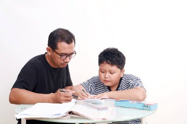 Asyalı okul çocuğu babasıyla evde çalışıyor.
