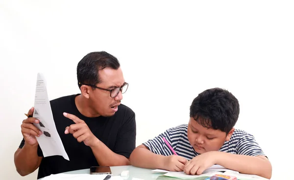 アジア系の少年は怒っているお父さんと一緒に家で勉強する — ストック写真