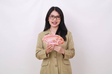 Kameraya bakarken Endonezya banknotlarını tutan mutlu Asyalı öğretmen. Beyazda izole edilmiş