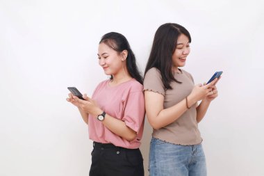 İki Asyalı kadın el ele tutuşup cep telefonlarıyla internette sohbet ediyorlar.