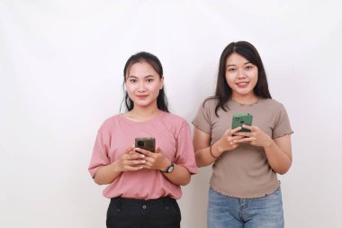 Kameraya bakarken cep telefonu tutan iki Asyalı kadın. Beyazda izole edilmiş