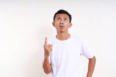 Asyalı komik adam yukarı bakıyor ve işaret ediyor. Beyaz arkaplanda izole