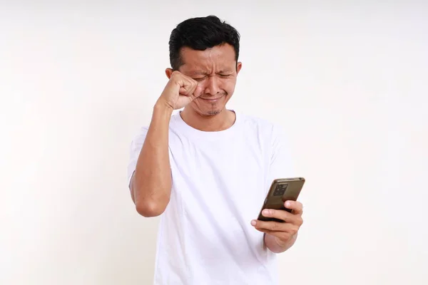 Грустный Азиатский Смешной Мужчина Плачет Держа Руках Телефон Изолированный Белом — стоковое фото