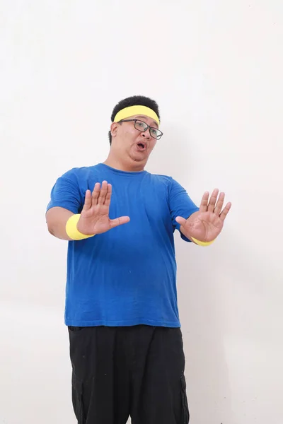 アジアの太りすぎの男でスポーツウェア立っている間否定的な手のジェスチャーを示します 白に隔離 — ストック写真