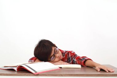Yorgun Asyalı öğrenci ders çalışırken masaya uzanıyor. Beyazda izole edilmiş