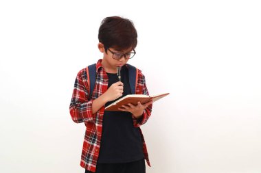 Düşünceli Asyalı öğrenci bir şeyler düşünürken elinde kitap tutuyor. Beyazda izole edilmiş