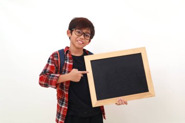Asyalı mutlu bir öğrenci elinde boş bir tahtayla dikilip işaret ediyor. Beyazda izole edilmiş