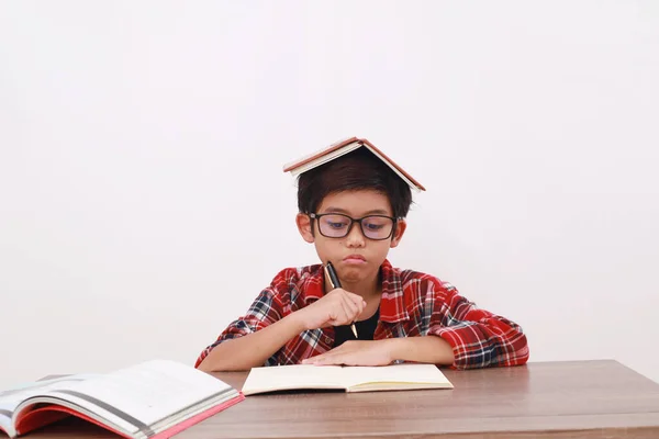 彼の頭の上に本を勉強しながら何かを考えているアジアの学生の思考 — ストック写真