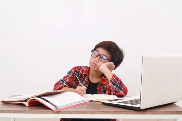 机の上で勉強しながら横に空の空間を見ている怠惰なアジアの学生 白に隔離された — ストック写真