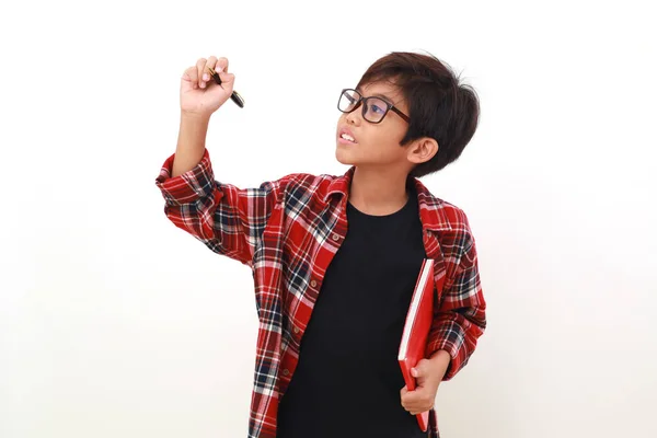 Förtjusande Asiatisk Pojke Som Håller Bok Medan Han Skriver Nåt — Stockfoto