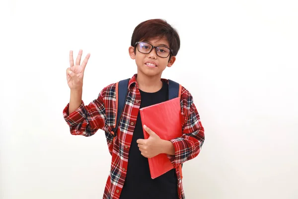 Feliz Chico Asiático Inteligente Sosteniendo Libro Mientras Muestra Tres Dedos — Foto de Stock