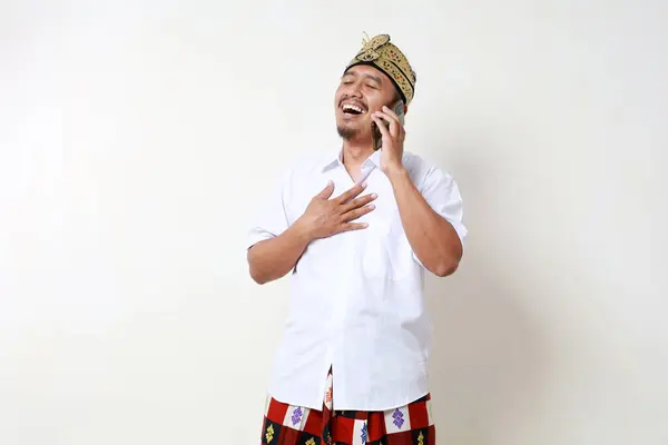 Счастливый Азиатский Мужчина Балийском Традиционном Костюме Держит Грудь Разговаривая Телефону — стоковое фото