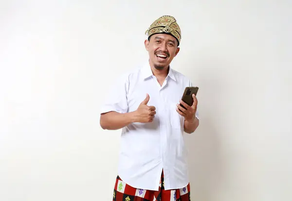 Feliz Hombre Asiático Traje Tradicional Balinés Sosteniendo Teléfono Celular Mientras —  Fotos de Stock