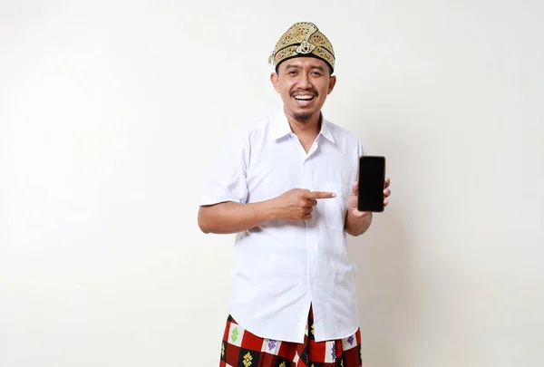 Возбужденный Азиат Балийском Традиционном Костюме Стоит Показывая Чистый Экран Мобильного — стоковое фото