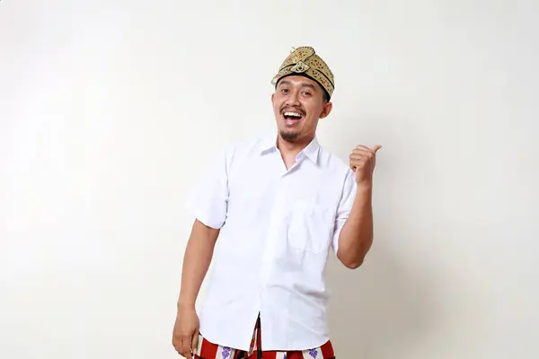 側面を提示しながら立っているバリニアの伝統的な衣装の幸せなアジア人男性 白い背景に隔離される — ストック写真
