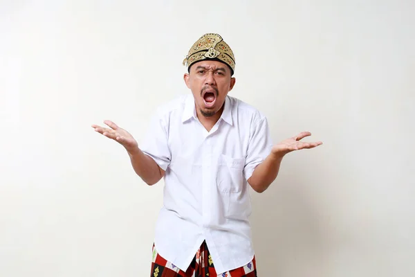 悲鳴を上げながら立っているバリニアの伝統衣装のアジア人男性 白い背景に隔離される — ストック写真