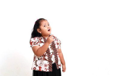 Batik 'li sevimli Asyalı küçük kız yanlamasına işaret etti. Beyaz arkaplanda izole