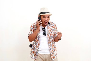 Kızgın Asyalı yetişkin turist telefonda konuşurken ayakta duruyor. Seyahat kavramı. Beyaz arkaplanda izole