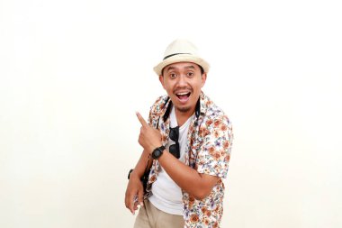 Arkasındaki boşluğu göstererek duran Asyalı yetişkin turistin heyecanlı ifadesi. Seyahat kavramı. Beyaz arkaplanda izole