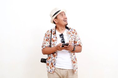 Boş alanda bir şeyler ararken elinde cep telefonu olan mutlu Asyalı yetişkin bir turist. Seyahat kavramı. Beyaz arkaplanda izole