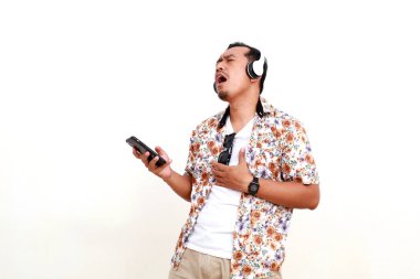 Asyalı gezgin kulaklıkla müzik dinlerken şarkı söylüyor. Kopyalama alanı ile beyaz arkaplanda izole