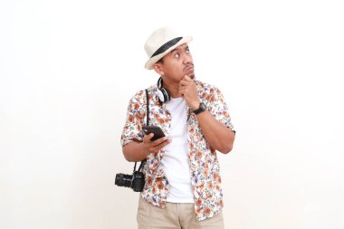 Kafası karışmış Asyalı gezgin cep telefonu tutarken bir şeyler düşünüyor. Kopyalama alanı ile beyaz arkaplanda izole