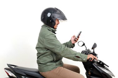 Motosiklet sürerken Asyalı bir adamın cep telefonu kullanışının yan görüntüsü. Beyaz arkaplanda izole
