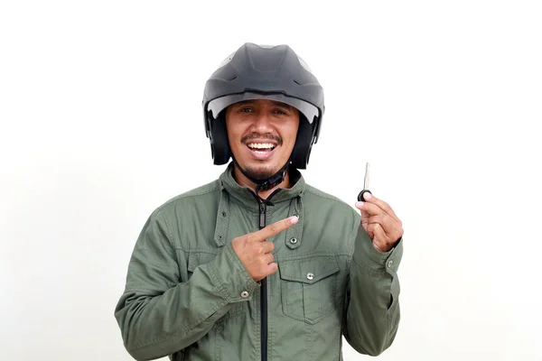 Motosiklet anahtarı tutarken ceket ve kask giyen mutlu Asyalı adam. Beyaz arkaplanda izole