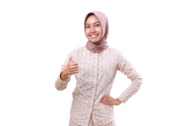 Asyalı genç müslüman kadın başparmağını kaldırarak ayakta duruyor. Beyaz arkaplanda izole