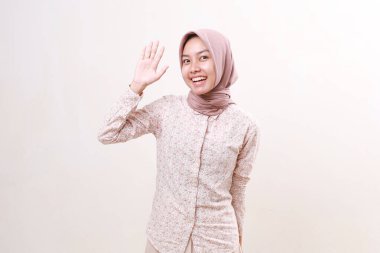 Mutlu, genç Asyalı Müslüman kadın elini kaldırırken konsepti selamlıyor. Beyazda izole edilmiş