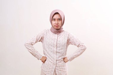 Kızgın Asyalı genç Müslüman kadın mutsuz bir ifadeyle kameraya bakıyor. Beyazda izole edilmiş