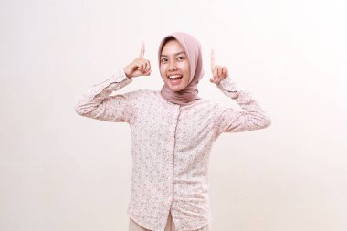 Yukarıyı göstererek ayakta duran mutlu Asyalı genç Müslüman kadın. Beyazda izole edilmiş